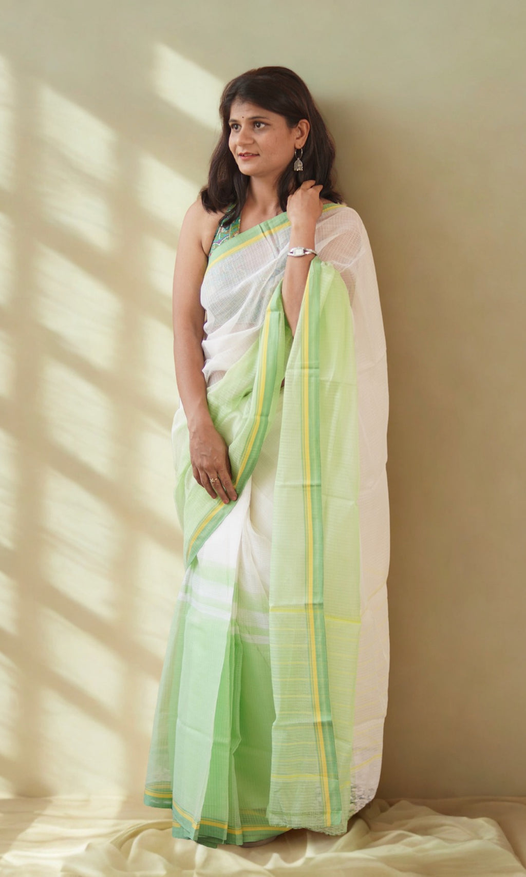 Model wearing an off-white with pastel green yellow border Kota Doria handloom saree from Rajasthan