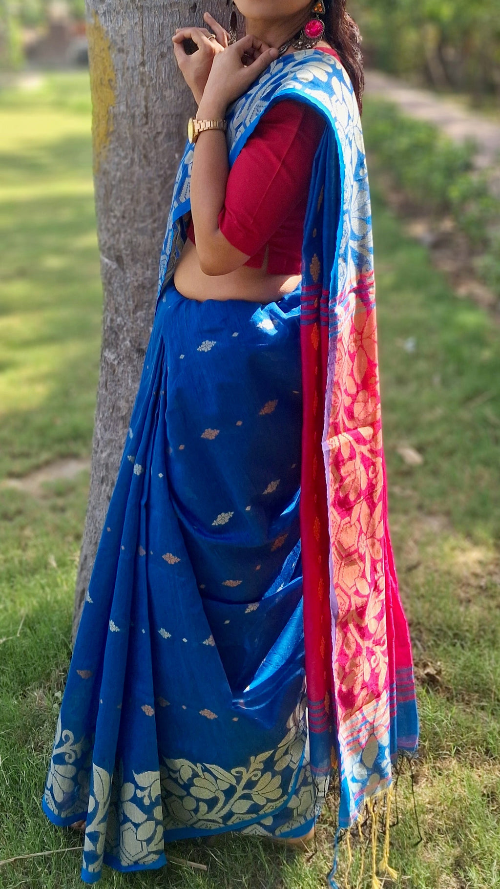 pleats of Handwoven blue Shantipuri Tant saree with woven motifs and contrasting red pallu.