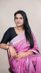 border close-up view of handwoven magenta Kanjivaram silk saree with gold buttas and lavender zari border draped on model
