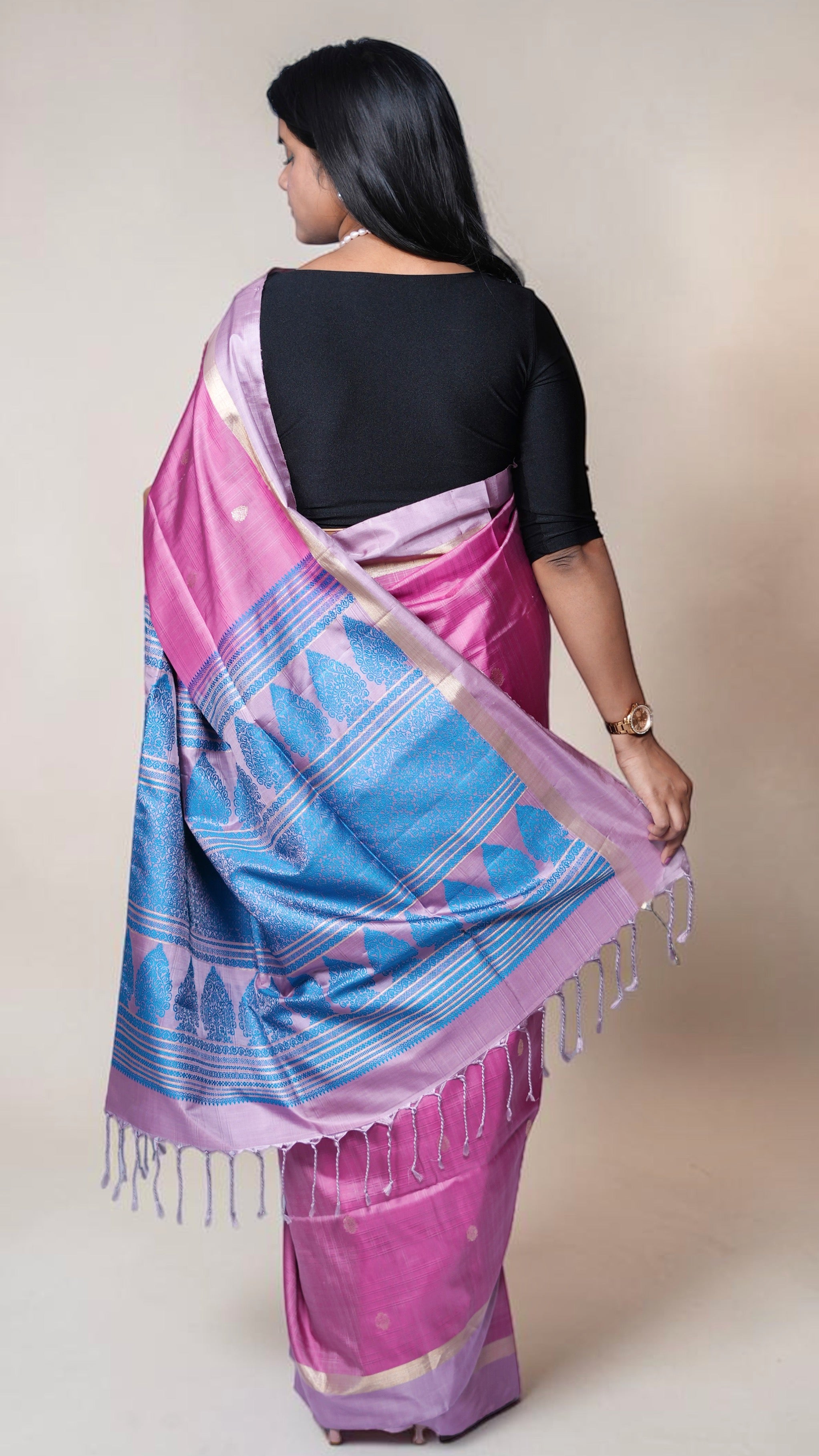 pallu details of handwoven magenta Kanjivaram silk saree with gold buttas and lavender zari border draped on model
