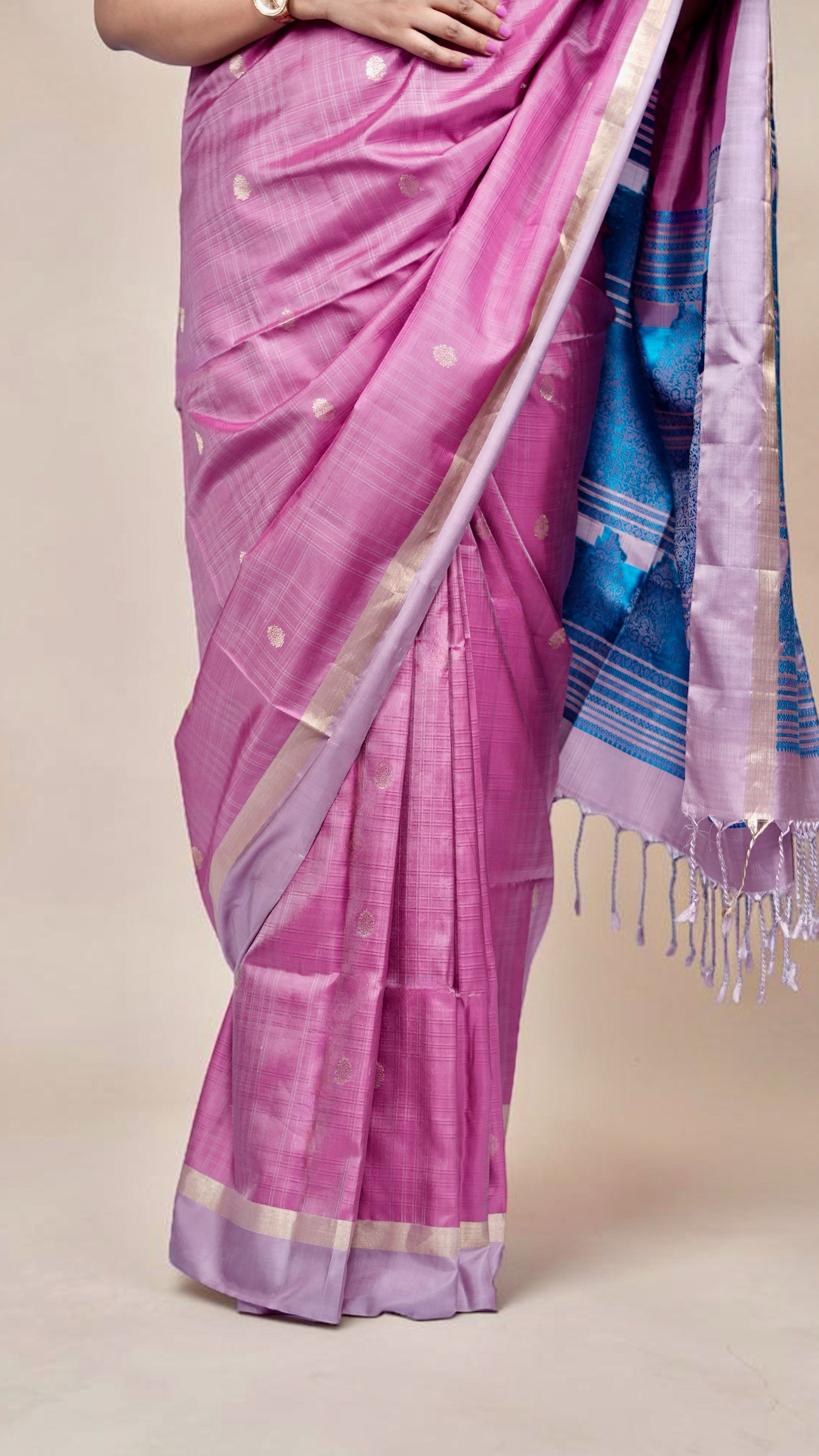 close-up of pleats of handwoven magenta Kanjivaram silk saree with gold buttas and lavender zari border draped on model