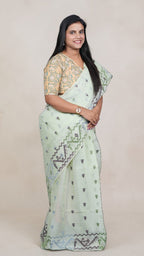 left view of model draped in a mint green Baluchari Taant cotton saree with jacquard-woven motifs from West Bengal.