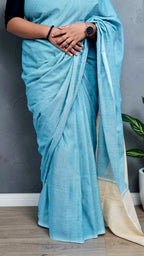 pleats close up view of model wearing soft aqua blue khadi cotton handloom saree with natural beige border woven in West Bengal.