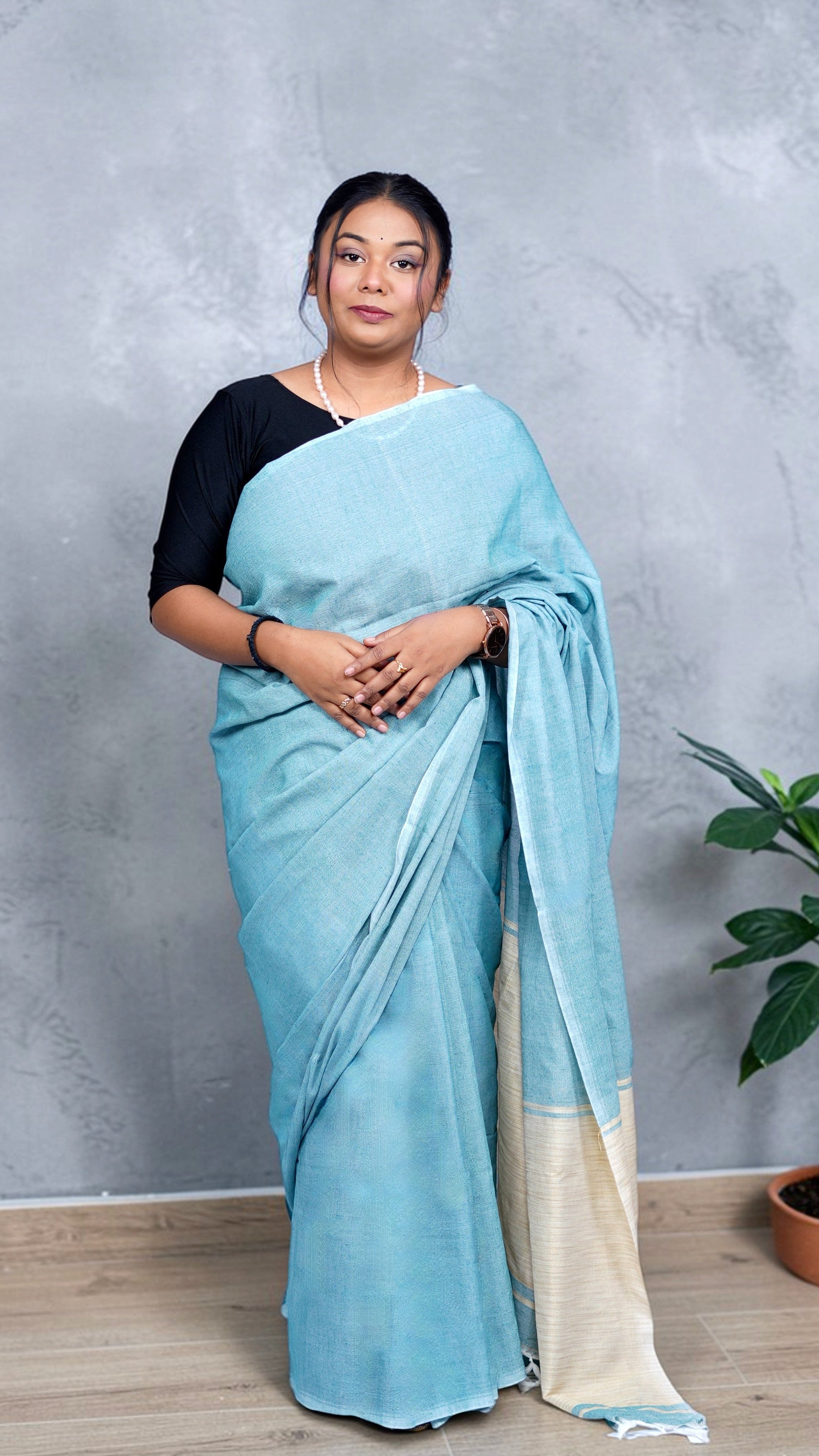 Model wearing soft aqua blue khadi cotton handloom saree with natural beige border woven in West Bengal