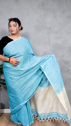 Left view of model wearing soft aqua blue khadi cotton handloom saree with natural beige border woven in West Bengal