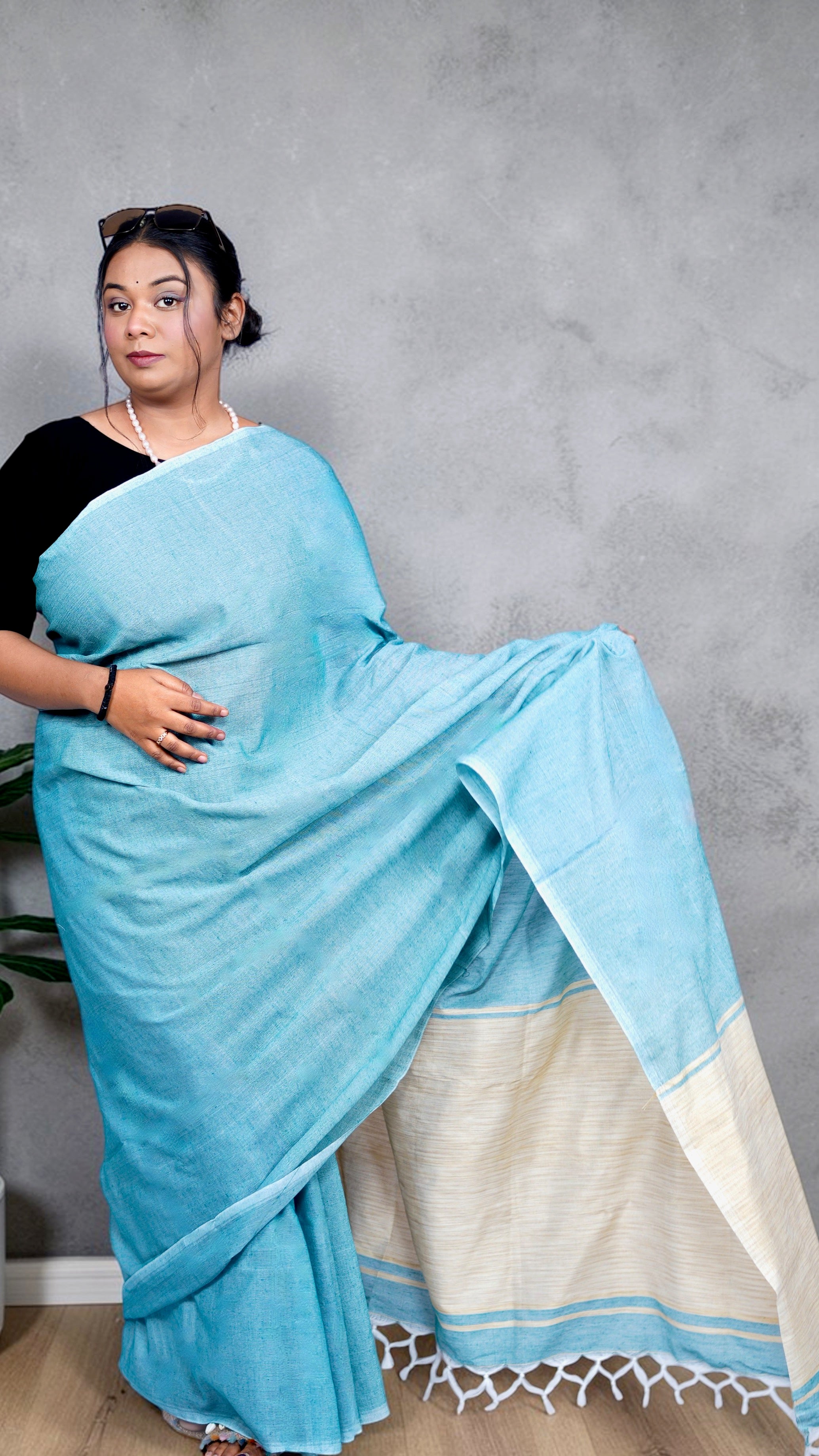 Left view of model wearing soft aqua blue khadi cotton handloom saree with natural beige border woven in West Bengal
